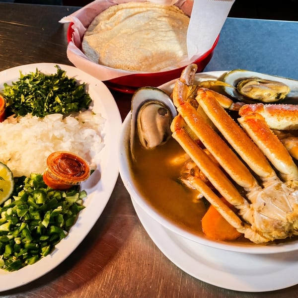Seafood soup with crab legs, shrimp, and mussels, served with rice, limes, jalapeños, and tortillas.